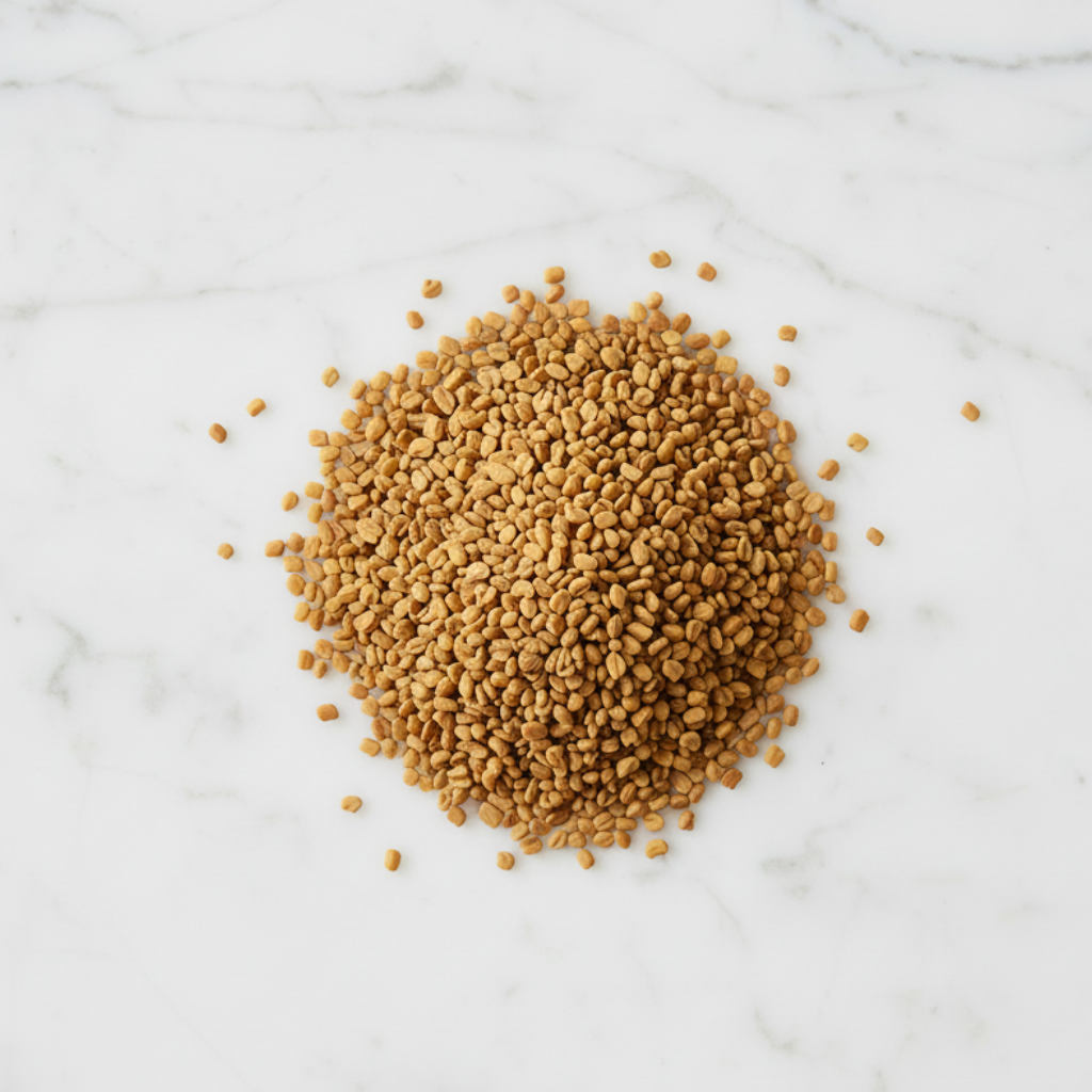 Top-Down View of Maison Gabrielle Whole Fenugreek Seeds, Showcasing the Golden-Amber Color and Angular Texture of this Artisanal Spice on a White Marble Surface